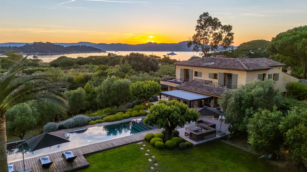 Aerial view at sunset — the villa, pool and garden above the bay of Saint-Tropez, the sun low over the water