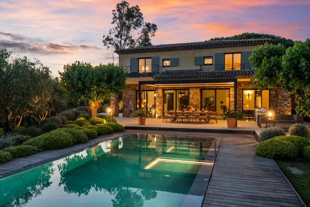 The villa's lit loggia and plunge pool beneath a fiery twilight sky