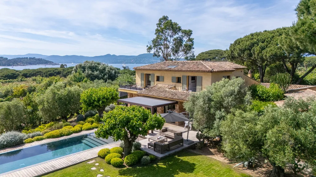 Elevated daytime view of the villa and pool, the bay of Saint-Tropez beyond the olive garden