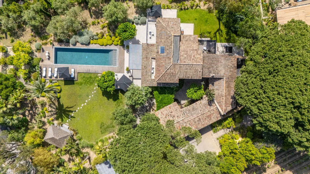 Overhead daytime view of the pool, lawn and tiled roofs among the greenery