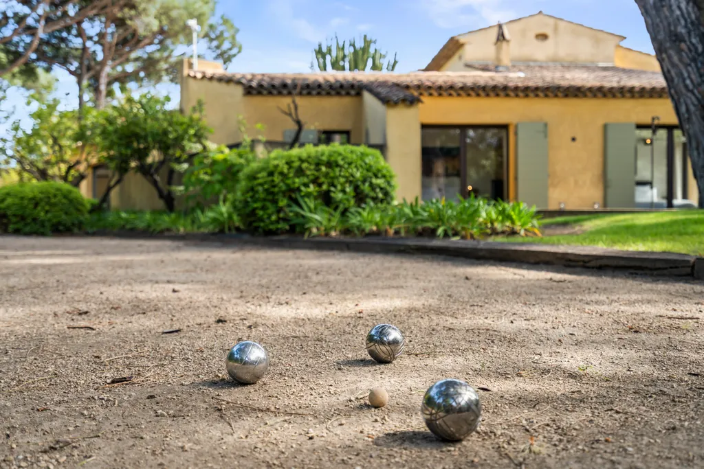 Petanque boules resting on the gravel court, the villa's façade behind
