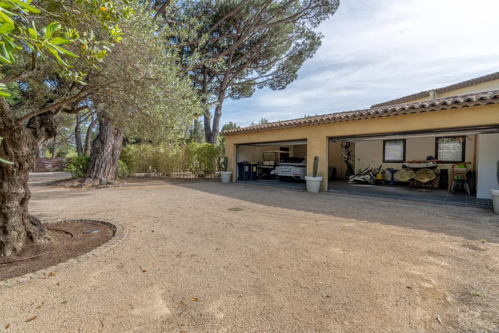 The villa's double garage and gravel forecourt beneath a parasol pine
