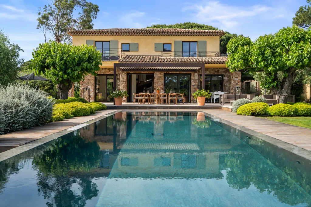 The villa's loggia mirrored in the pool beneath a clear blue sky