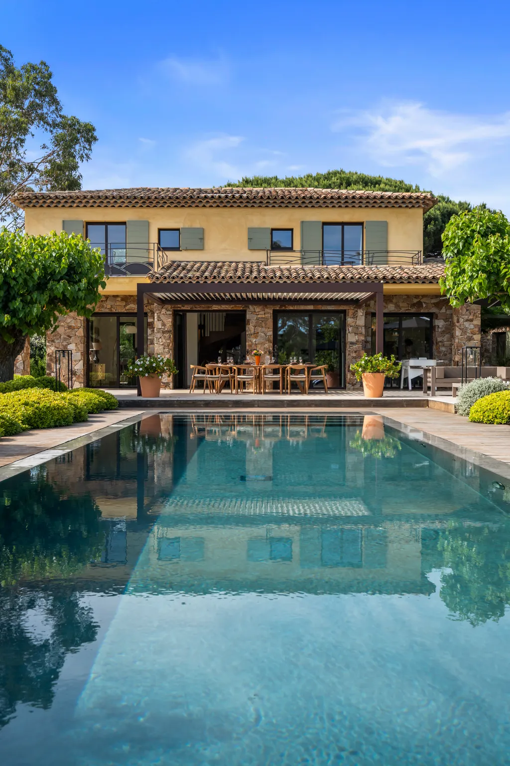 The villa's façade and dining loggia reflected in the length of the pool